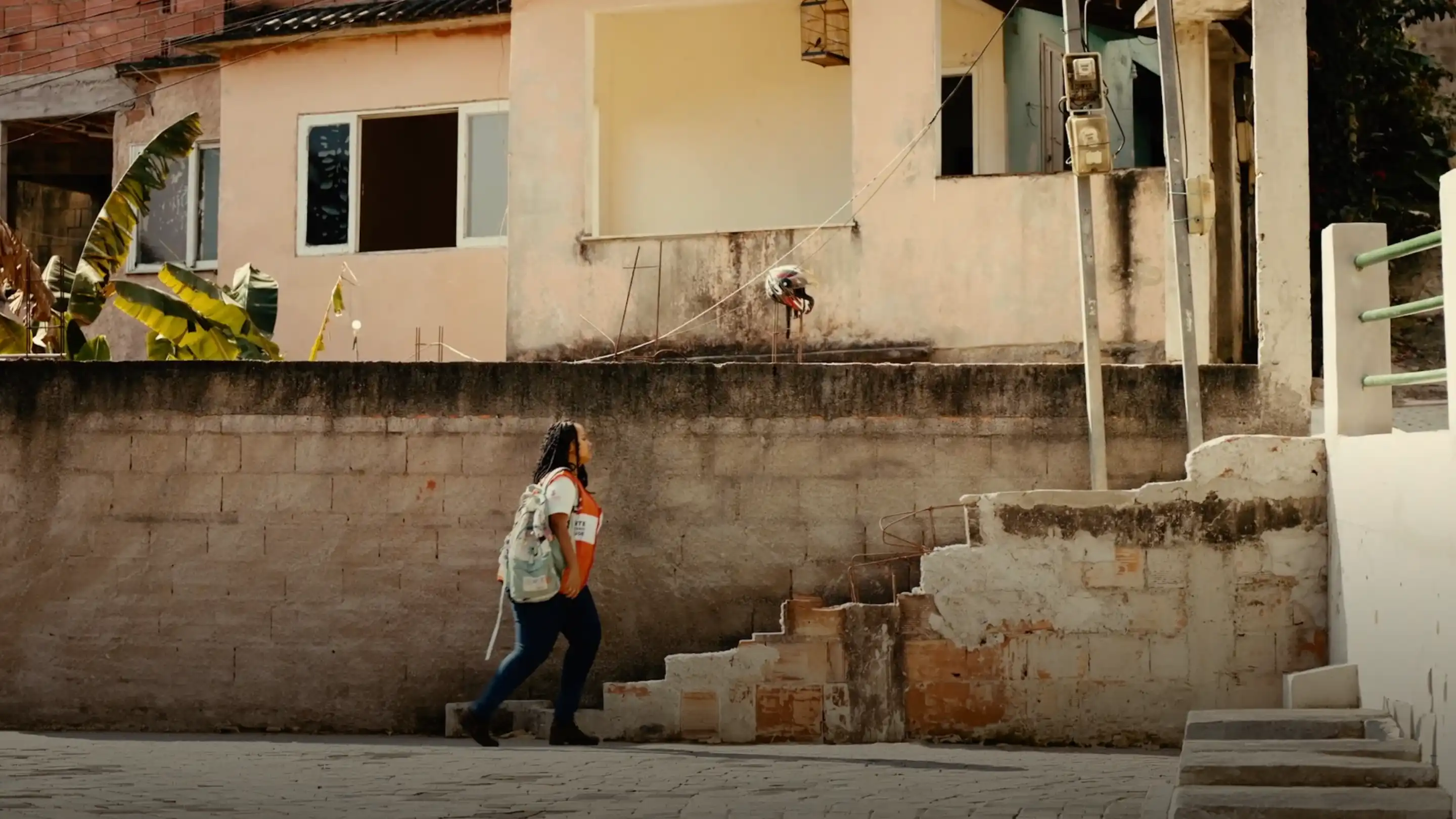 Woman walking up stairs next to a beige building with a concrete wall and stairs.