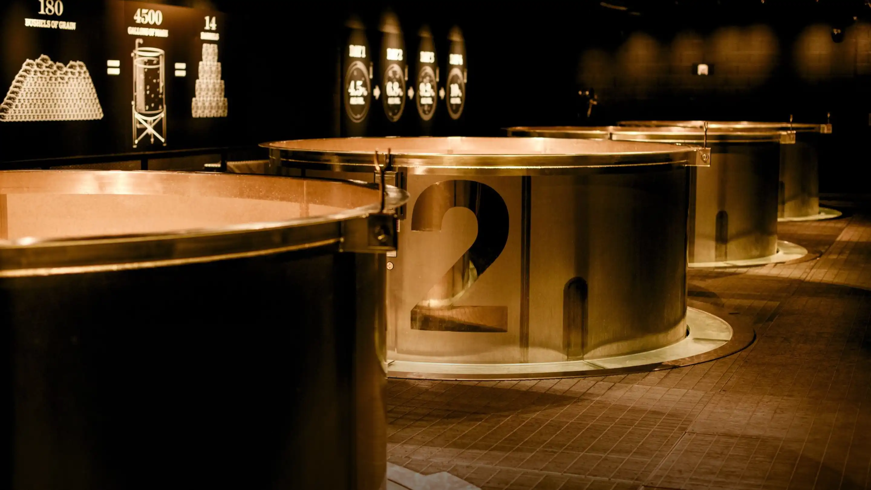 Large metallic circular structures numbered 1 and 2 in a dimly lit exhibition space.